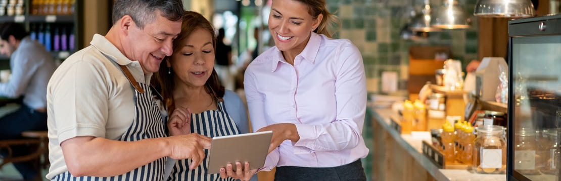 Business owners in discussion looking at a tablet.