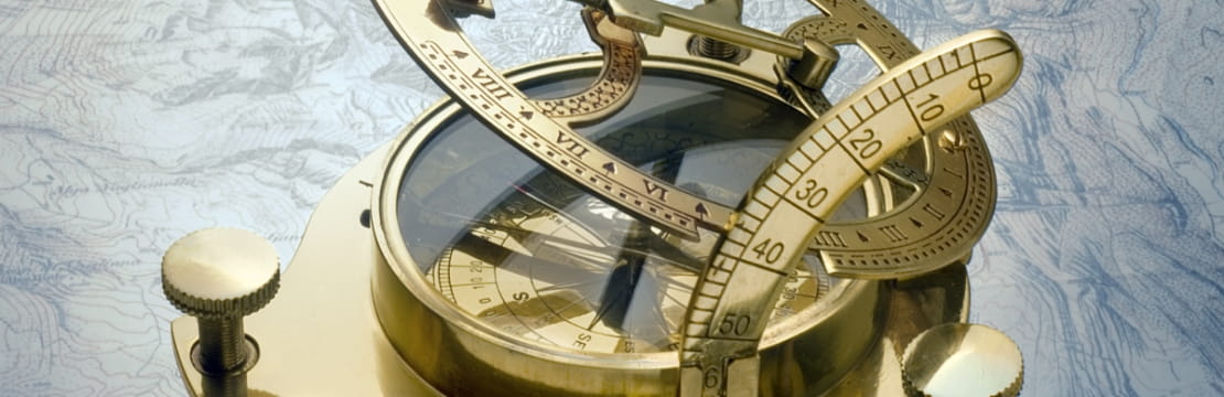 A close-up of a gold compass resting on a map.